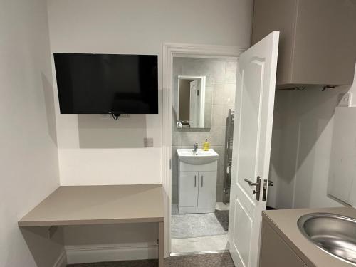 a bathroom with a sink and a tv on the wall at Unique Modern, 1 Bed Flat, 15 Mins To Central London in Hendon