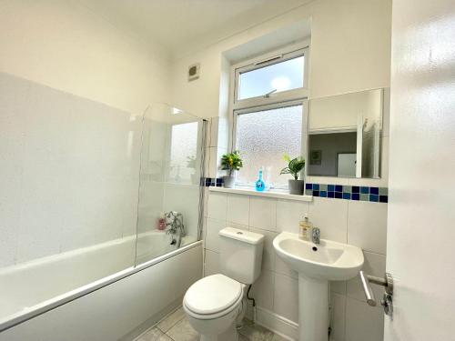 biała łazienka z toaletą i umywalką w obiekcie 4 Bedrooms, 3 bathrooms , Reception, Kitchen, Garden, FullHouse w Londynie