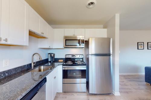 a kitchen with white cabinets and a stainless steel refrigerator at Sonesta 203 in Ocean City