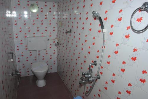 a bathroom with a toilet and red flowers on the wall at Just Guest House, Chennai Airport in Chennai