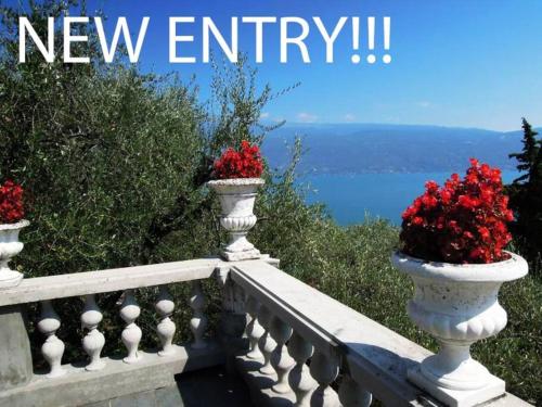 a white railing with two vases filled with red flowers at Villa Pinetina in Gargnano