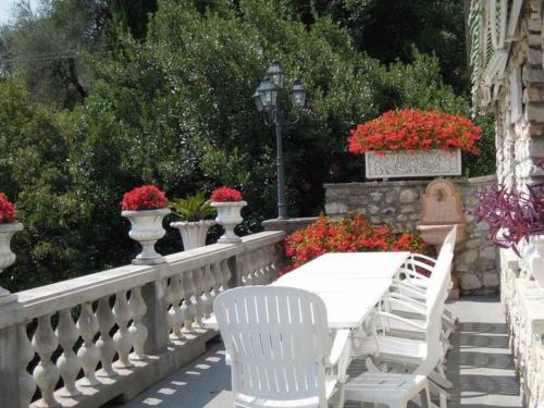 a white table and chairs on a fence with flowers at Villa Pinetina in Gargnano