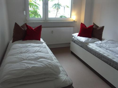 two beds in a room with red pillows on them at GWG City Apartments II in Halle an der Saale