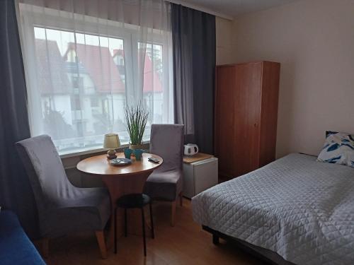 een slaapkamer met een tafel, een bed en een raam bij Willa 13-nastka in Międzyzdroje