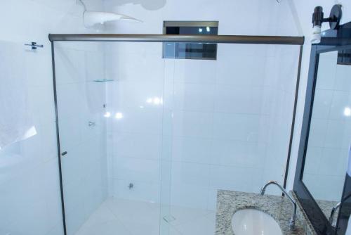 a glass shower stall with a sink in a bathroom at Hotel Iguaçu Centro in Foz do Iguaçu