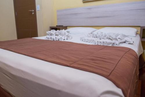 a bed with white towels on top of it at Hotel Iguaçu Centro in Foz do Iguaçu