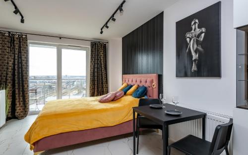 a bedroom with a bed and a table and a window at LoveRoom Panorama Park Jacuzzi in Białystok