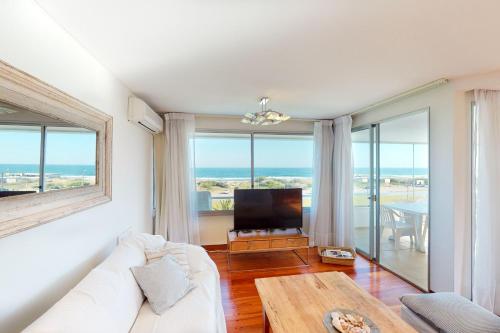 a living room with a white couch and a tv at Oceana Suites en Esturion, frente a playa Brava in Punta del Este