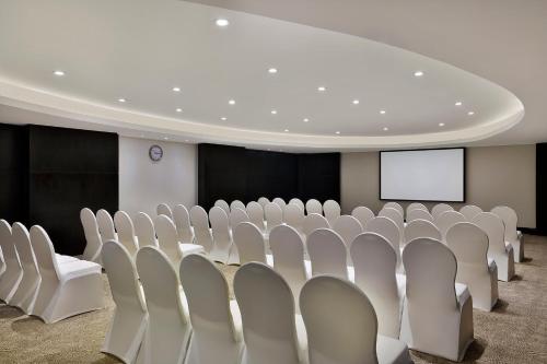 a conference room with white chairs and a screen at Voco - Riyadh by IHG in Riyadh