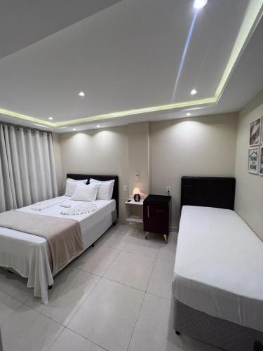 a hotel room with two beds and a night stand at Pousada Arraial Tropical in Arraial do Cabo