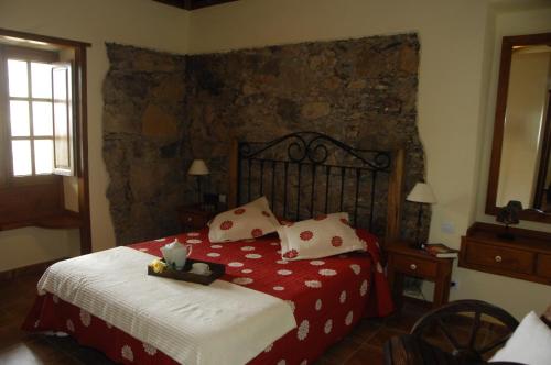um quarto com uma cama grande com lençóis vermelhos e brancos em Casa rural Las Palmeras em Vallehermoso