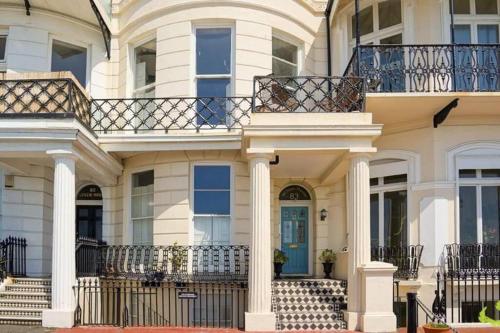 Una gran casa blanca con columnas y una puerta azul en Stunning seafront apartment, en Brighton & Hove
