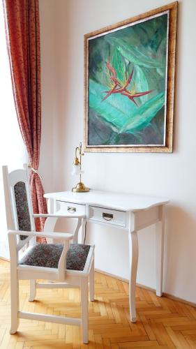 a white desk with a chair and a painting on the wall at Hotel U Zlateho jelena in Prague