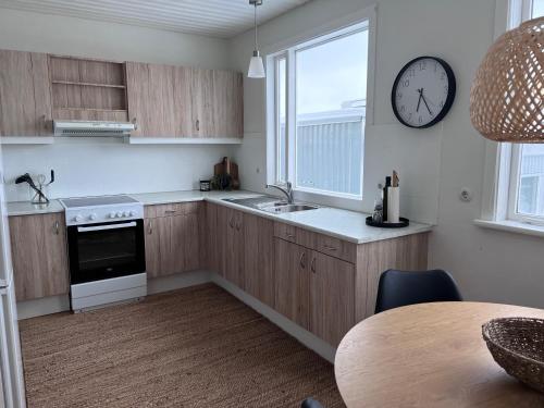 a kitchen with wooden cabinets and a clock on the wall at Akureyri apartments in Akureyri