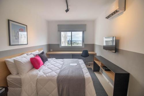 Dormitorio con cama, escritorio y TV en Housi - Metropolitan Sidney Smart Style en Goiânia