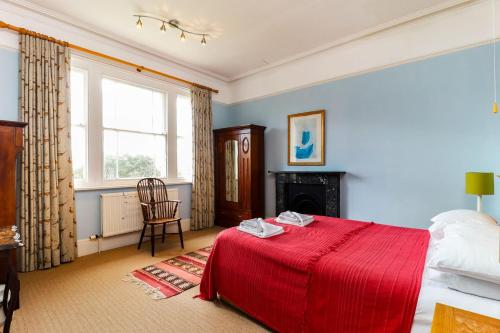 a bedroom with a red bed and a fireplace at Downedge in Brading