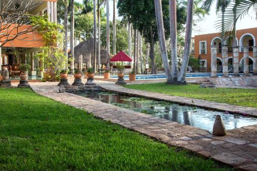 a garden with a pond in front of a building at Hacienda Uxmal Plantation & Museum in Uxmal