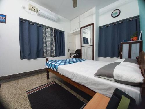 a bedroom with a large bed with blue curtains at Nature 2BHK AC Villa - Trivandrum in Trivandrum