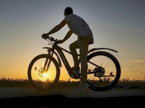 un hombre montando una bicicleta delante de la puesta de sol en Apartment SÄLEN II, en Stöten