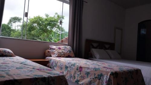 a hotel room with two beds and a window at Refúgio Ouro Fino Kitnets Casas e Apartamentos in Paraty