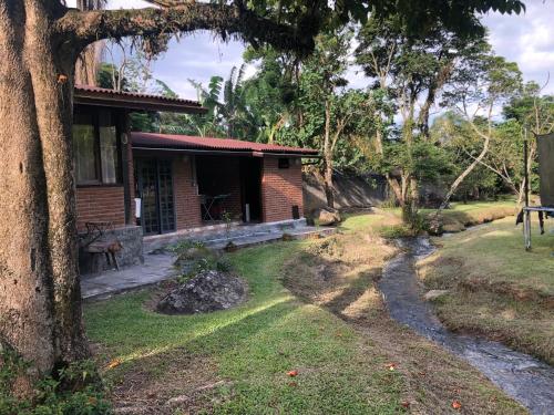 una pequeña casa de ladrillo con un árbol en primer plano en Sítio Solar di Stella en Itatiaia