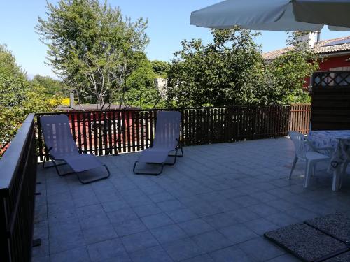 eine Terrasse mit Stühlen, einem Tisch und einem Sonnenschirm in der Unterkunft Falco Bianco in San Daniele del Friuli