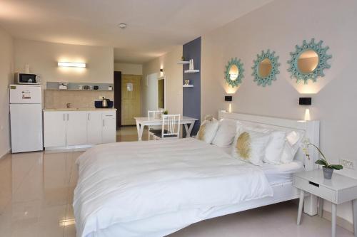 a bedroom with a large white bed and a kitchen at אדם וחווה - סוויטות מפנקות עם ג'קוזי פרטי ובריכה במתחם מול נוף גלילי מושלם in Gornot HaGalil