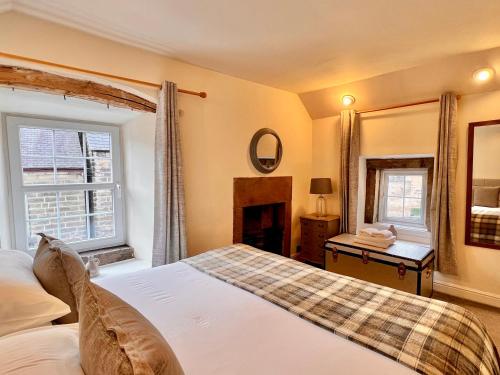 a bedroom with a bed and a fireplace and a mirror at Gate Cottage in Matlock