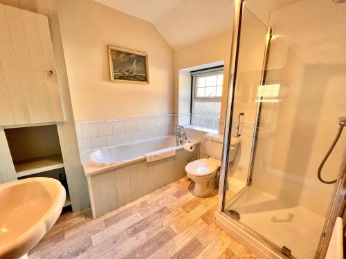 a bathroom with a tub and a toilet and a sink at Jewel Cottage in Matlock