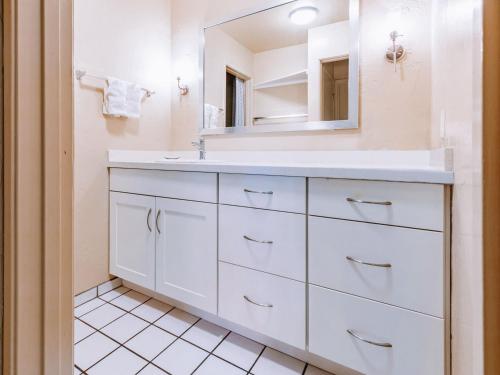 La salle de bains est pourvue d'un lavabo blanc et d'un miroir. dans l'établissement Plantation Hale Suites, à Kapaa