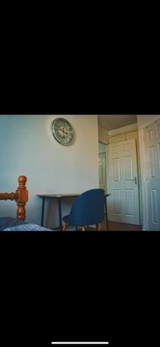 a room with a table and a blue chair and a clock at Detached House with a private en suite room in Clydebank