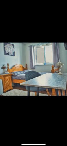 een woonkamer met een bed en een tafel bij Detached House with a private en suite room in Clydebank
