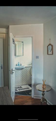 uma casa de banho com um lavatório e uma mesa num quarto em Detached House with a private en suite room em Clydebank