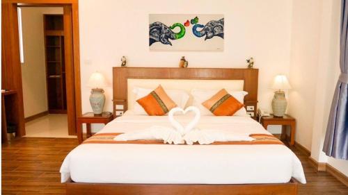a bedroom with a large white bed with a bow on it at Aura Samui Best Beach Hotel - SHA Plus in Lamai