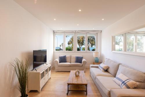 uma sala de estar com um sofá e uma televisão em Sea View with Parking by LU&CIA em Málaga