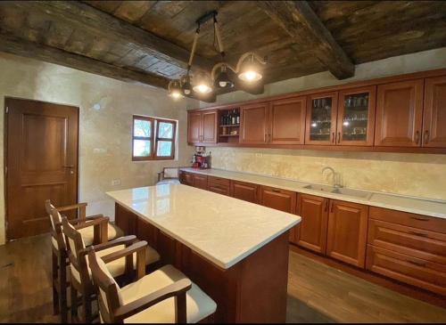 a kitchen with wooden cabinets and a island with chairs at OLIVE QUEEN Rustic Apartment 1 in Bar