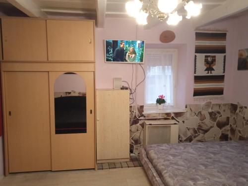 um quarto com uma cama e uma televisão na parede em Liána Vendégház em Szilvásvárad