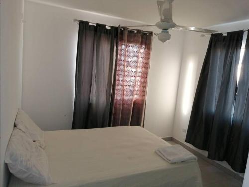a white bed in a room with black curtains at Sweet Alar in La Estrella