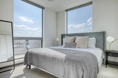 une chambre avec un grand lit et de grandes fenêtres dans l'établissement Logan Sq 2BR w Roof Gym 1 block to L CHI-480, à Chicago