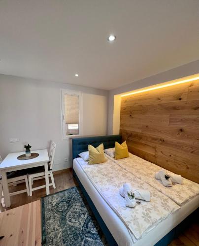 マラガにあるApartamentos Prestige Málaga Suitesのベッドルーム1室(木製ヘッドボードとテーブル付きのベッド1台付)