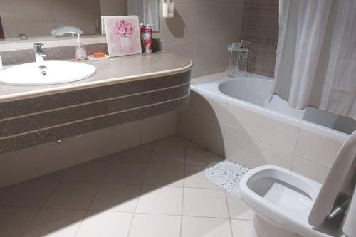 a bathroom with a sink and a toilet and a tub at stunning 2-bedroom flat in Ajman 