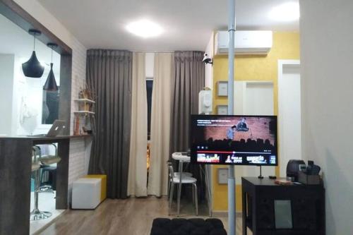 ein Wohnzimmer mit einem TV und einem Tisch mit einem Stuhl in der Unterkunft Apartamento completo próximo aeroporto e rodoviária de POA in Canoas