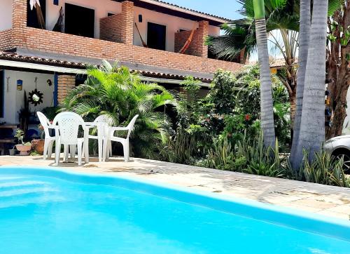 twee stoelen en een tafel naast een zwembad bij Pousada dos Anjos Paracuru in Paracuru
