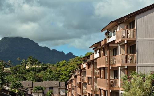 a building with balconies and a mountain in the background at Banyan Harbor Resort in Lihue