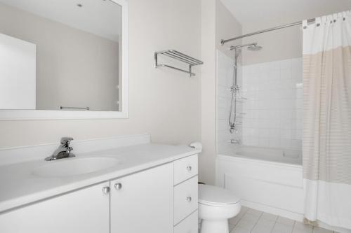 a white bathroom with a sink and a toilet and a tub at Loop 2BR w Gym Doorman same block as L CHI-673 in Chicago