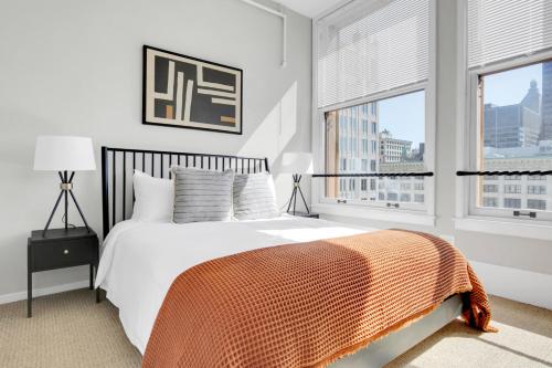 a bedroom with a bed with an orange blanket and two windows at Loop 2BR w Gym Doorman same block as L CHI-673 in Chicago