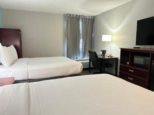 a hotel room with two beds and a desk with a television at Clarion Inn & Suites Grand Rapids Airport in Grand Rapids