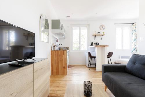 un salon avec un canapé et une télévision et une cuisine dans l'établissement Bel appart quartier Lardenne, à Toulouse