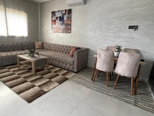 ein Wohnzimmer mit einem Sofa, einem Tisch und Stühlen in der Unterkunft Paradis Mahdia in Kenitra