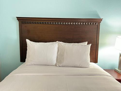 a bed with a wooden headboard and white pillows at Clarion Inn & Suites Grand Rapids Airport in Grand Rapids